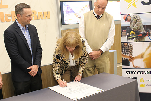 Alecia Grady, P30 Director, signs the partnership agreement with Freeport-McMoRan. Also shown are Ryan Niesz, Freeport’s Director of Compensation, left, and Patrick Kuykendall, Army Reserve Ambassador.