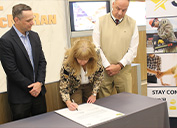 Alecia Grady, P30 Director, signs the partnership agreement with Freeport-McMoRan. Also shown are Ryan Niesz, Freeport’s Director of Compensation, left, and Patrick Kuykendall, Army Reserve Ambassador.