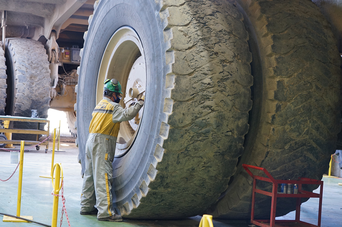 Photo of male by a large haul truck tire